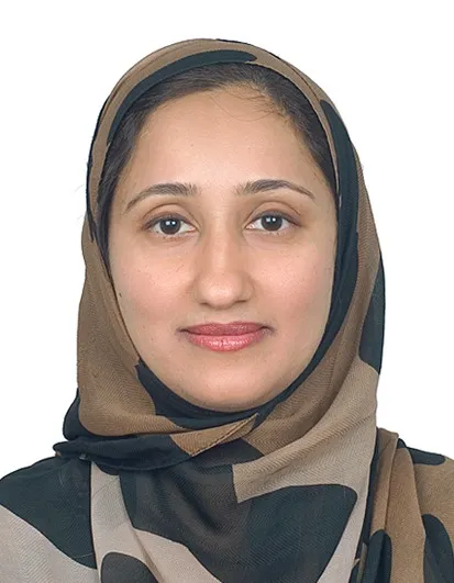 Dr. Rifat Mazhar Falak, smiling, in a brown and black patterned headscarf